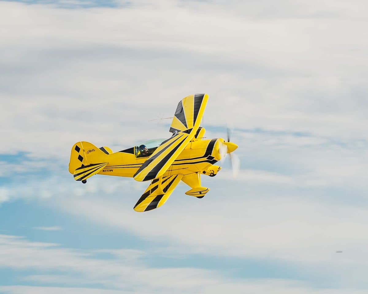 Yellow aerobatic biplane banking in flight